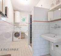 A bathroom in a family house with a shower, sink, washing machine, and boiler.