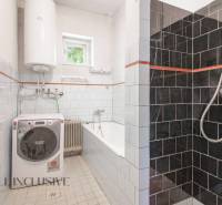 A bathroom in a family house with a shower, a washing machine, and a bathtub, tiled with tiles.