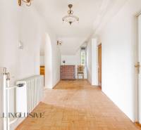 A spacious hallway with wooden flooring and furniture in a family house.