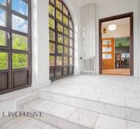 A bright hallway with large windows and an entrance to the living room in a family house.