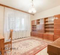 A room in a family house with a carpet, a wardrobe, and a table, illuminated by daylight.