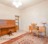 Interior of a family house with a piano, carpet, writing desk, and chair.
