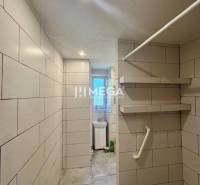 Bathroom hallway with tiles, shelves, and a washing machine in a studio apartment.