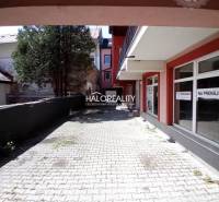 Commercial premises in Brezno with a paved sidewalk and trees in the background.