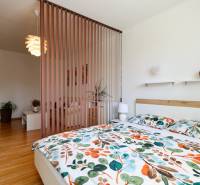 Bedroom in a 2-room apartment with patterned bed linen and wooden flooring.