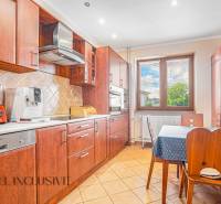 A kitchen in a family house with wooden furniture, appliances, and a dining table.