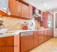 A kitchen with wooden cabinets, a ceramic sink, and appliances in a family house.