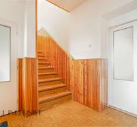 The family house has a hallway with a staircase and wooden paneling.