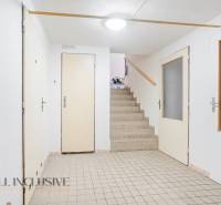 Interior with a hallway and staircase in a family house, white doors and tiles.