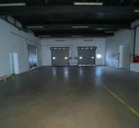 An empty interior of an industrial hall with two large rolling doors.