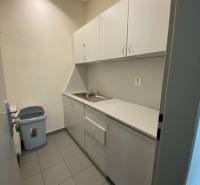 Kitchen corner in a warehouse with white cabinets and a sink.