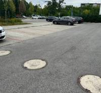 Parking lot on Za dráhou Street in Pezinok with cars and trees in the background.