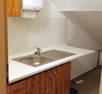 An office with a sink, cabinets, and a trash can for practical dishwashing.