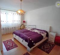 Bedroom in a family house with a large bed, nightstands, and decorative rugs.