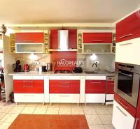 A kitchen with red and white elements in a family house, equipped with appliances and cabinets.