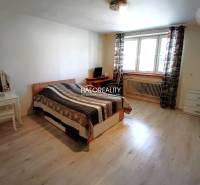 A room in a family house with a bed, a table, and a window with a view outside.