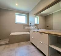A bathroom in a family house with a bathtub and a large mirror, neutral shades.