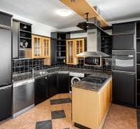 A kitchen in a 4-room apartment with dark cabinets and appliances, a sunny window on the right.