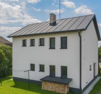 A family house in Pruské with a white facade, wood for heating, and a lawn.