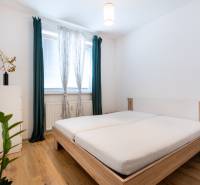 A bright bedroom with a wooden bed and nightstands in a two-room apartment.