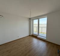 A room in a 2-bedroom apartment with a wooden floor and a large window to the balcony.