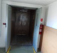 A large elevator opening in a manufacturing area with a fire extinguisher on the wall.