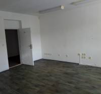 An empty interior of a manufacturing space with wooden flooring and open doors.