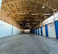 Interior of warehouses and halls with high ceilings, steel beams, and a row of lights.
