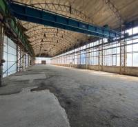 A spacious interior in an industrial hall with storage options and large windows.