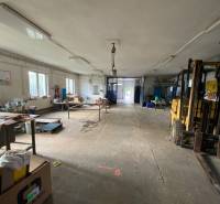 Interior of a warehouse and hall with workbenches and a forklift in the corner of the room.