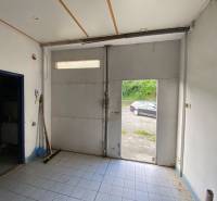 Interiors of warehouses and halls with open doors and a view of a car outside.