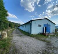 Warehouses and halls in Považská Bystrica, surrounded by greenery and a blue sky.