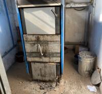 An industrial boiler in a boiler room of warehouses and halls with ash on the ground.