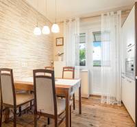Dining area with a wooden table and chairs in a 2-room apartment, decorated with brick cladding.