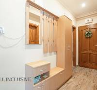 The entrance hall of a 2-room apartment with wooden furniture, a mirror, and wall hooks.