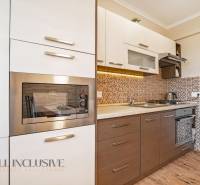 Modern kitchen in a 2-room apartment with wooden flooring and built-in appliances.