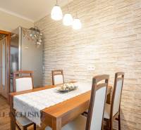 Dining room in a 2-room apartment with a wooden table and brick wall cladding.