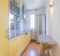 A kitchen in a 3-room apartment with wooden flooring, modern appliances, and a bar counter.