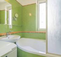 A bathroom with green tiles and a bathtub in a 3-room apartment.