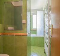 A bathroom with green tiles and a bathtub in a 3-room apartment.