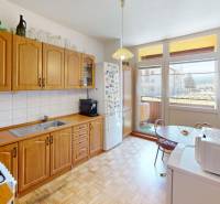A kitchen in a 3-room apartment with wooden cabinets, a table, and access to a balcony.