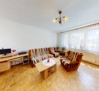 Living room in a three-room apartment with wooden flooring, a sofa set, and a desk.