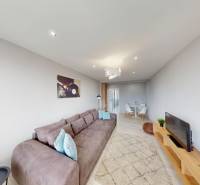 Living room in a two-room apartment with a sofa, television, and dining table.