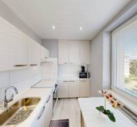 A kitchen in a 2-room apartment with light cabinets and a view from the window.