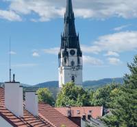Spišská Nová Ves, view of the church from Hviezdoslavova Street, surrounded by greenery and rooftops.