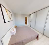 A bedroom in a 2-room apartment with a double bed, a painting, and a built-in wardrobe.