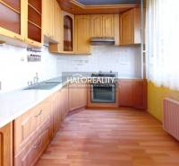 A kitchen with a wooden cabinet and appliances in a 3-room apartment, light tiles, curtains.