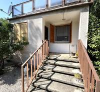 The exterior of the cottage in Radvaň nad Dunajom with a terrace and staircase, surrounded by greenery.