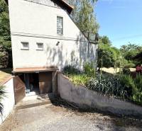 A cottage in Radvani nad Dunajom surrounded by greenery, with a wooden roof and an open garage.