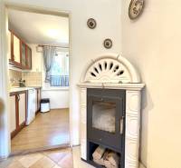 A fireplace in the interior of a cabin with a view of the kitchen and ceramic decorations on the wall.